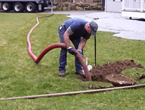 Septic pumping technician servicing a residential septic tank with a vacuum hose in Brandon, FL